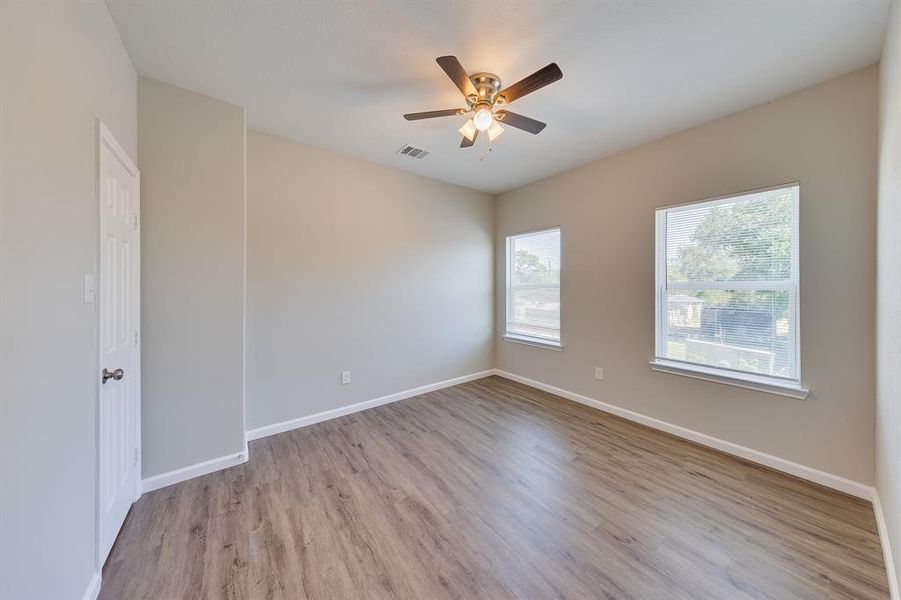 This bedroom is bathed in natural light thanks to two large windows that brighten the space and offer lovely outdoor views. The ample sunlight creates a warm, welcoming environment, making it an ideal retreat for rest and relaxation.