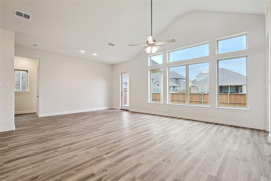 Unfurnished living room featuring light wood-type flooring, vaulted ceiling, and ceiling fan