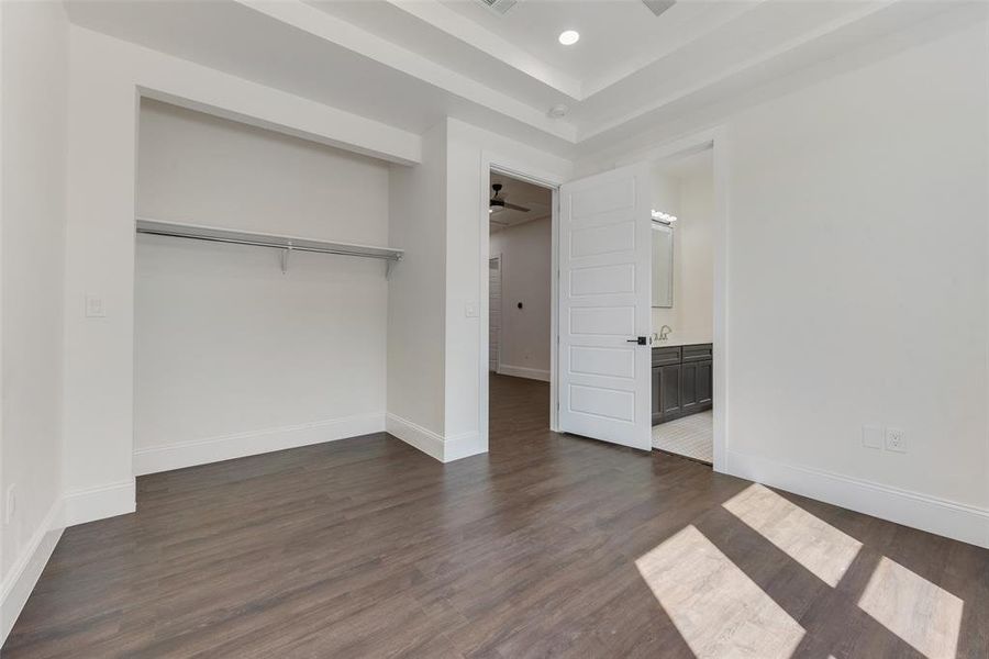 Unfurnished bedroom with dark wood-type flooring, a closet, and connected bathroom