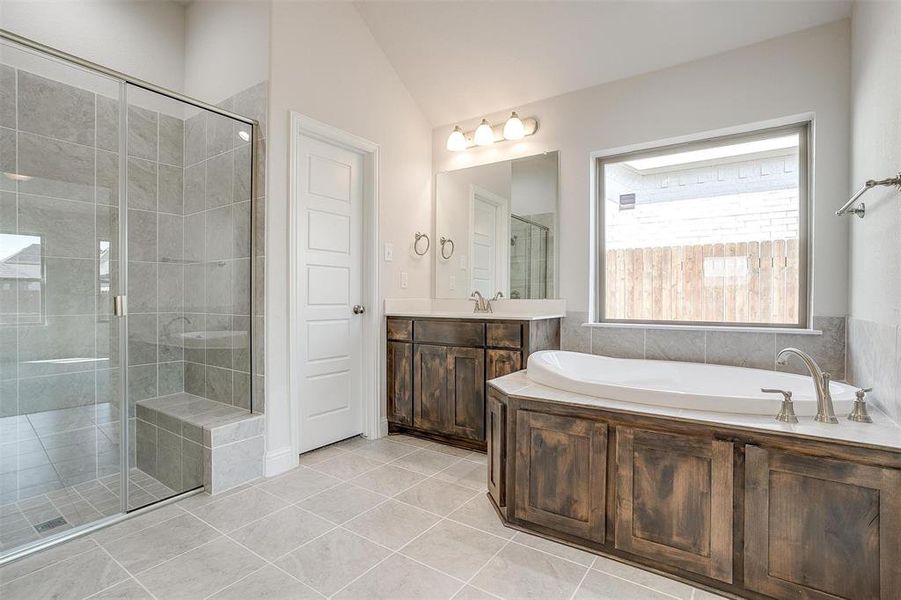 Bathroom with vanity, shower with separate bathtub, lofted ceiling, and tile patterned floors