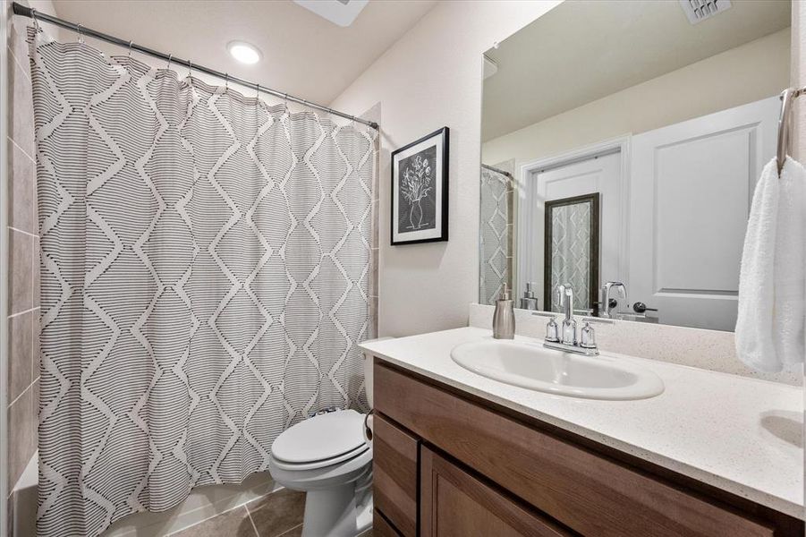 Full bathroom with vanity, toilet, tile patterned floors, and shower / bath combo with shower curtain