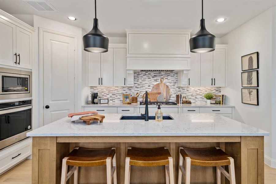 Kitchen featuring white cabinets, a kitchen island with sink, stainless steel appliances, and light stone countertops