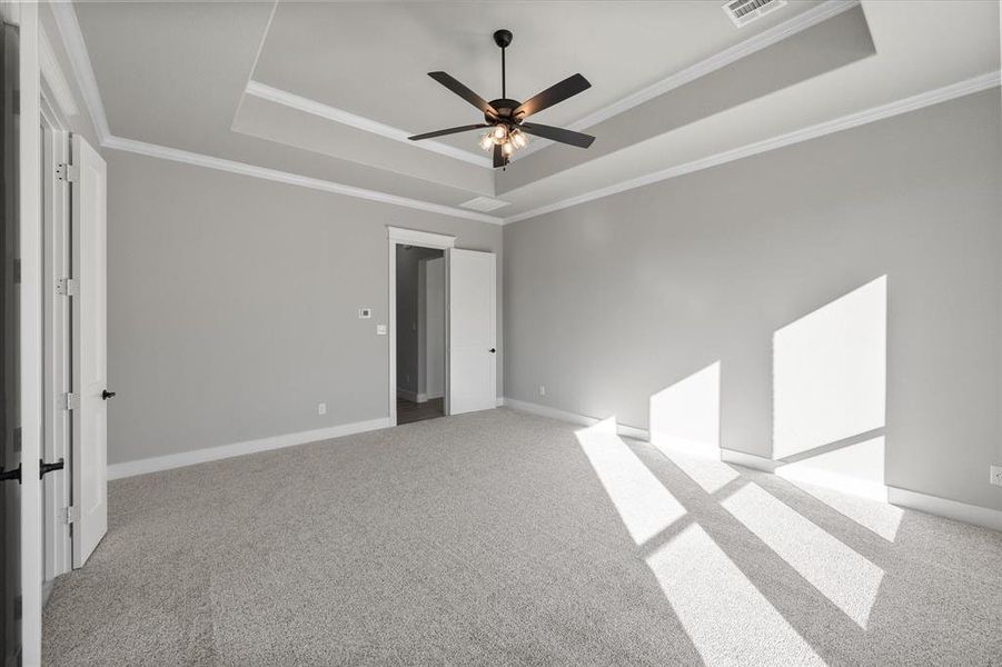 Primary suite with tray ceiling and crown molding. French doors to en-suite bathroom.