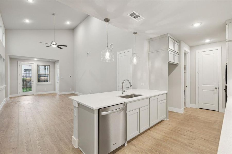 Kitchen with light hardwood / wood-style floors, sink, ceiling fan, a center island with sink, and stainless steel dishwasher