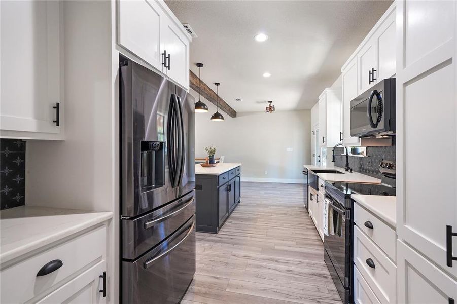 Kitchen with stainless steel fridge with ice dispenser, white cabinets, electric range, and light hardwood / wood-style floors