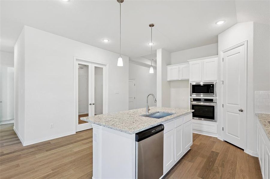 Kitchen with appliances with stainless steel finishes, light stone countertops, sink, and white cabinets