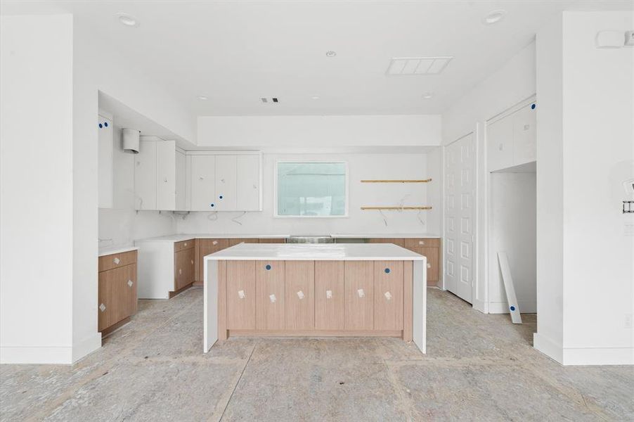 Waterfall quartz island, custom cabinetry, and stainless steel Bosch appliances throughout the kitchen