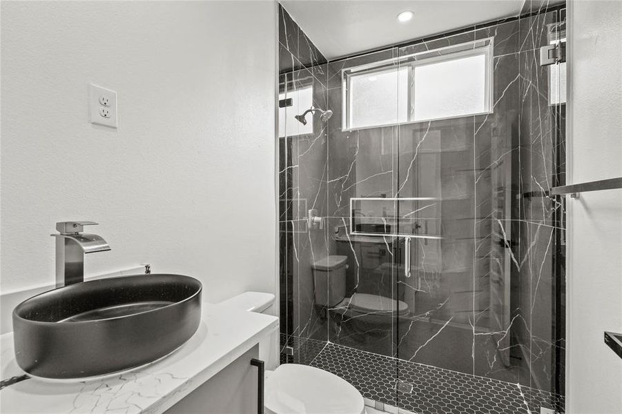 Bathroom featuring vanity, toilet, and a shower with door