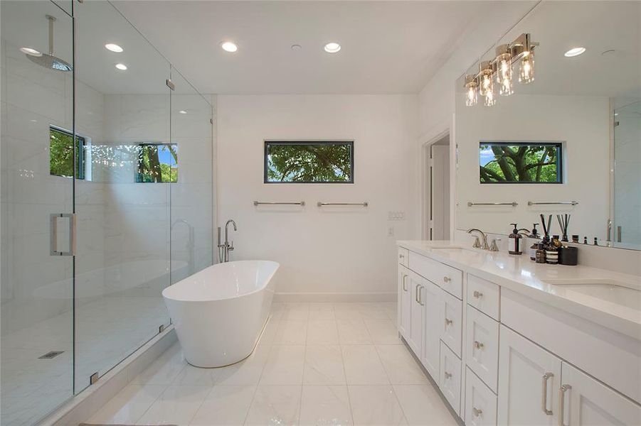 Bathroom featuring tile floors, vanity with extensive cabinet space, shower with separate bathtub, and dual sinks