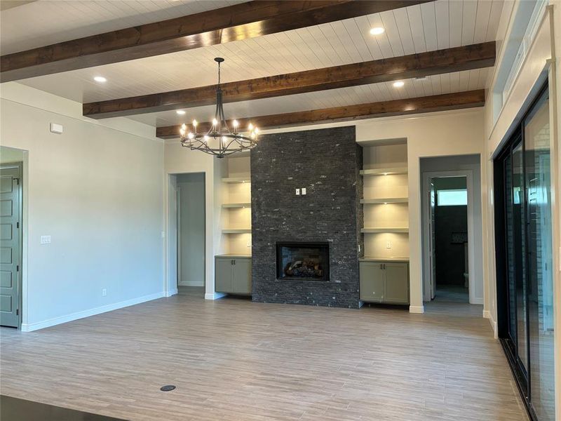 Unfurnished living room with built in shelves, beam ceiling, a fireplace, light hardwood / wood-style flooring, and wooden ceiling