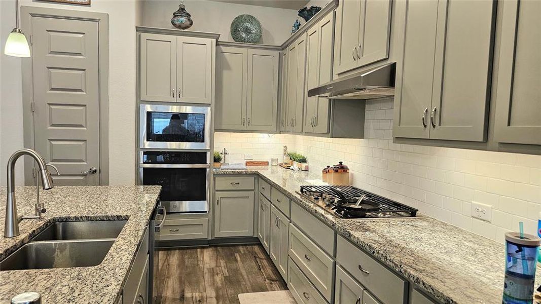 Kitchen featuring stainless steel appliances, wall chimney range hood, sink, pendant lighting.