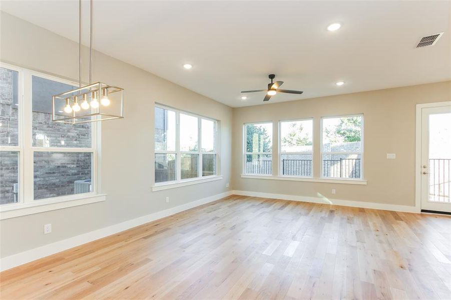 Unfurnished room with ceiling fan with notable chandelier and light hardwood / wood-style floors