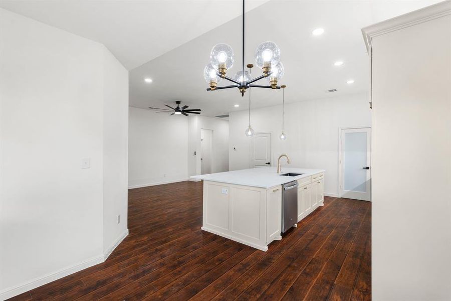 Kitchen with white cabinetry, dark hardwood / wood-style floors, ceiling fan with notable chandelier, and hanging light fixtures