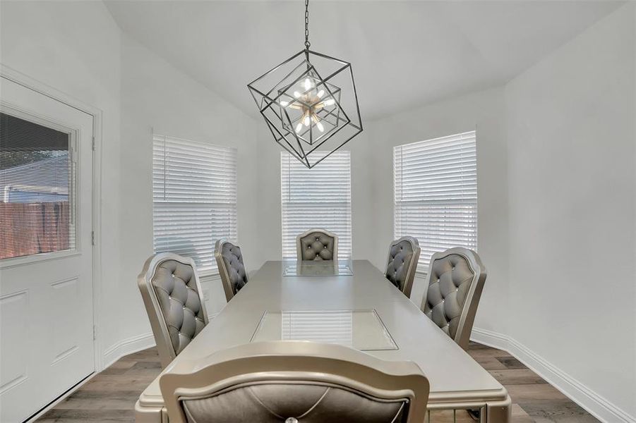 Dining area with dark hardwood / wood-style flooring, lofted ceiling, and a chandelier