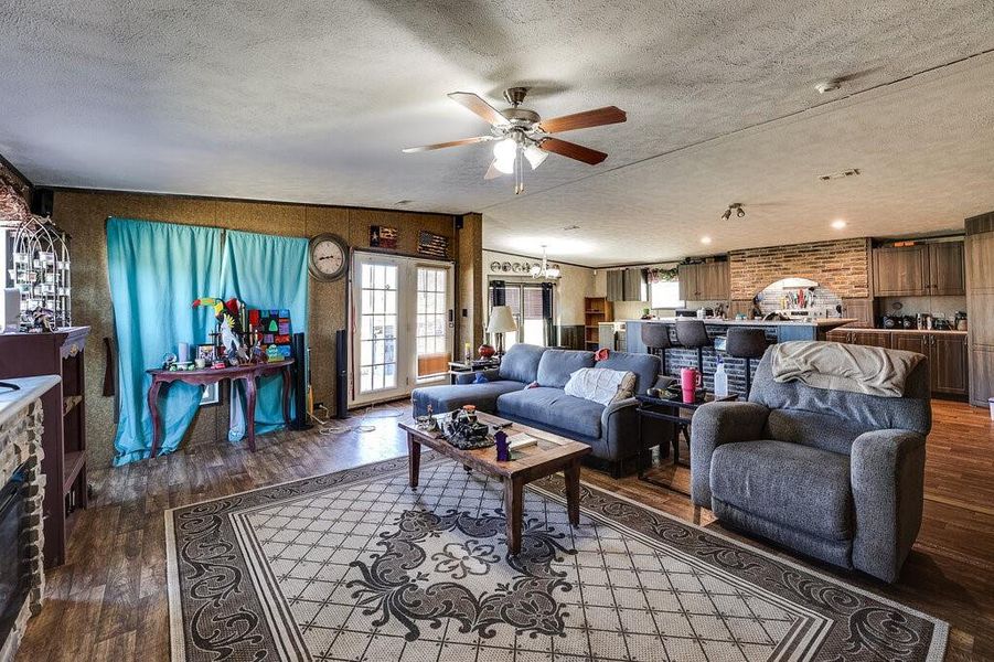 Living room with ceiling fan, a textured ceiling, and hardwood / wood-style flooring