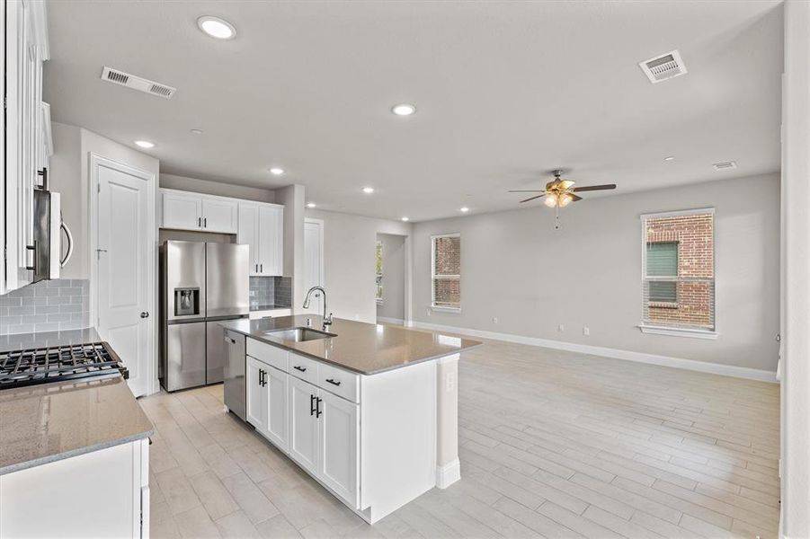 Kitchen featuring white cabinets, stainless steel appliances, a kitchen island with sink, and sink