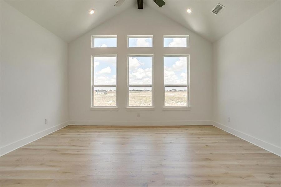 Empty room with light hardwood / wood-style flooring, ceiling fan, high vaulted ceiling, and beam ceiling