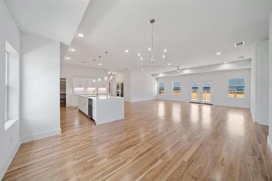 Unfurnished living room with light hardwood / wood-style floors, a notable chandelier, and sink