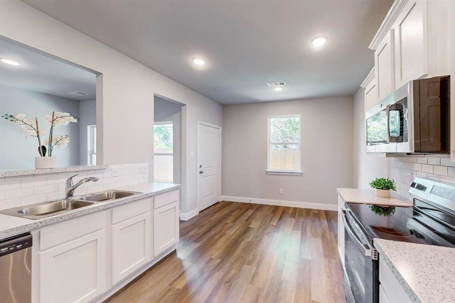 Kitchen featuring appliances with stainless steel finishes, white cabinetry, sink, and light hardwood / wood-style floors