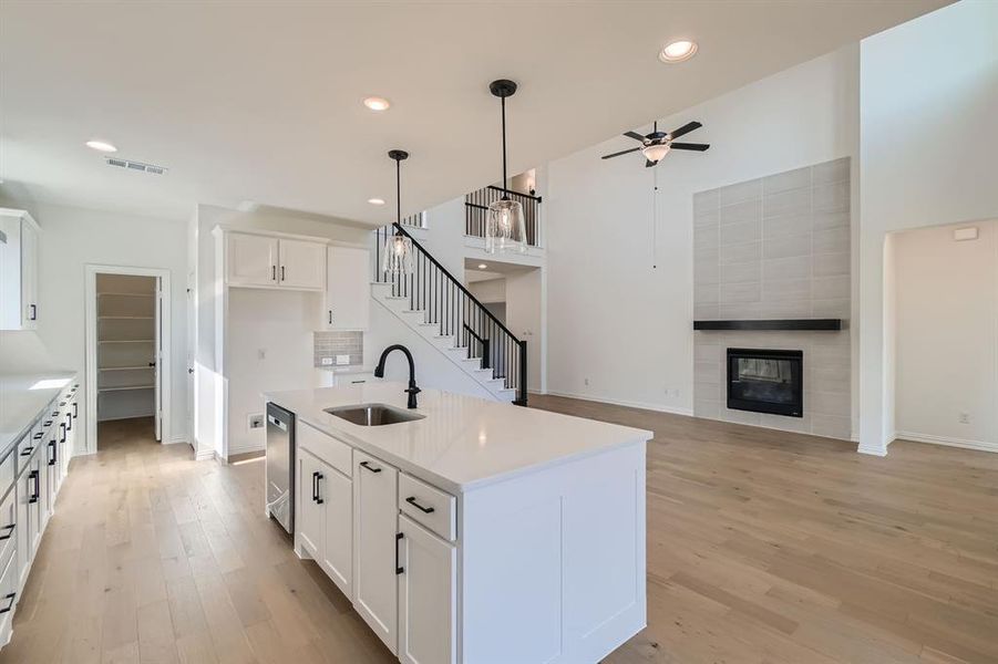 Kitchen featuring white cabinets, a kitchen island with sink, light wood-type flooring, pendant lighting, and sink