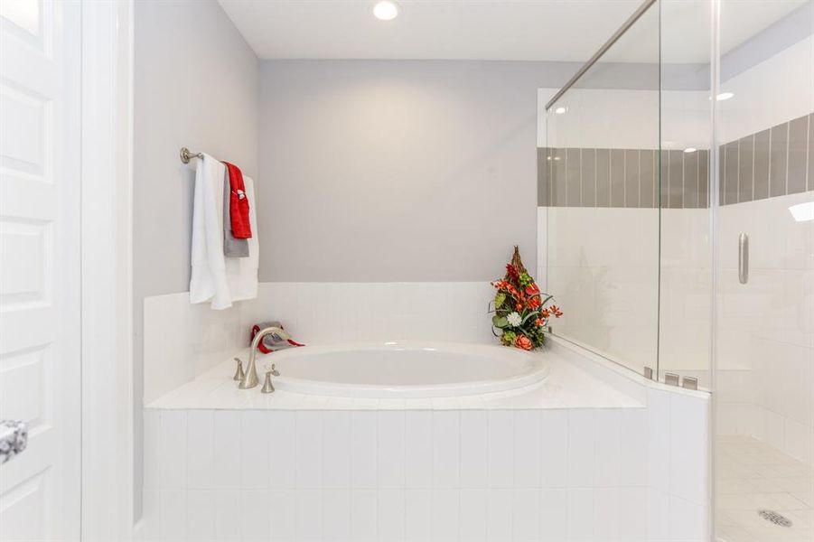 The ROClake's primary bathroom features a large shower and bathtub and dual vanities. The bright lighting fixtures and clean lines contribute to a serene, spa-like atmosphere.