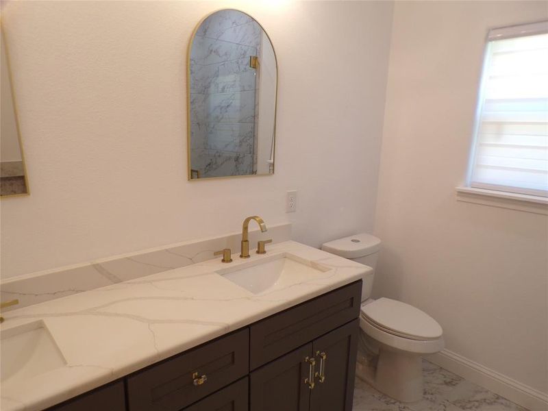 Bathroom with dual vanity, tile patterned floors, and toilet