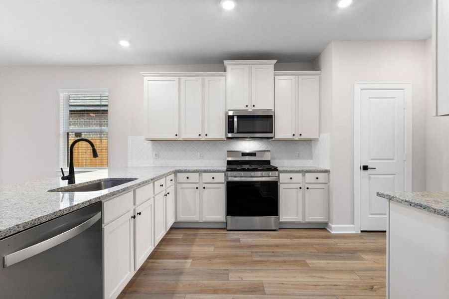 With its clean lines and minimalist aesthetic, the large kitchen exudes effortless chic, showcasing the crisp contrast between the white cabinets, sleek stainless-steel appliances, and luxurious granite countertops for a sophisticated yet approachable look.