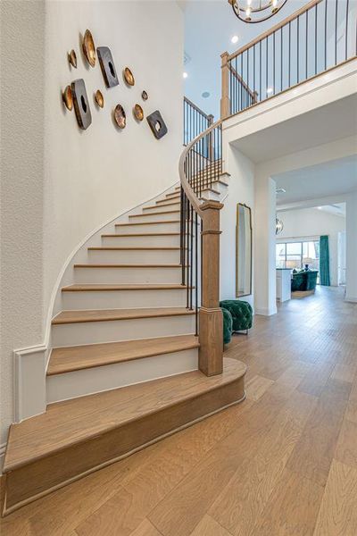 Stairs with hardwood / wood-style flooring and a notable chandelier