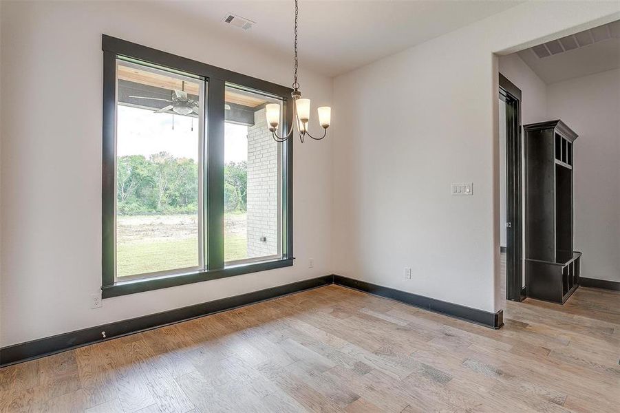 Unfurnished room with a notable chandelier and light hardwood / wood-style flooring