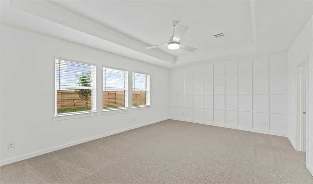 Primary bedroom with wall of windows and trayed ceilings. (*Photo not of actual home and used for illustration purposes only.)