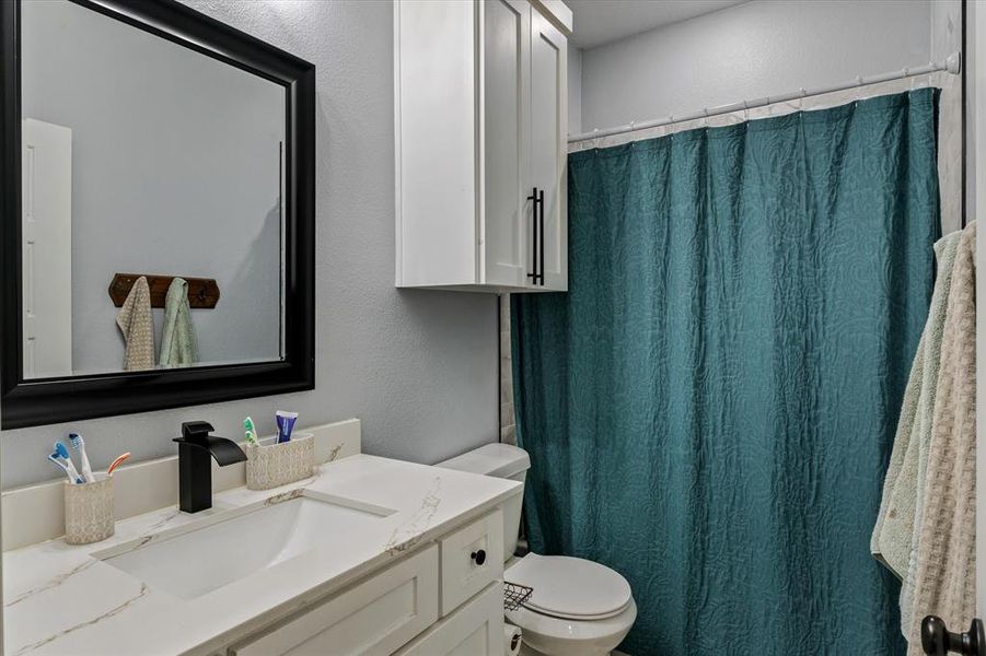 Bathroom with a shower with curtain, vanity, and toilet