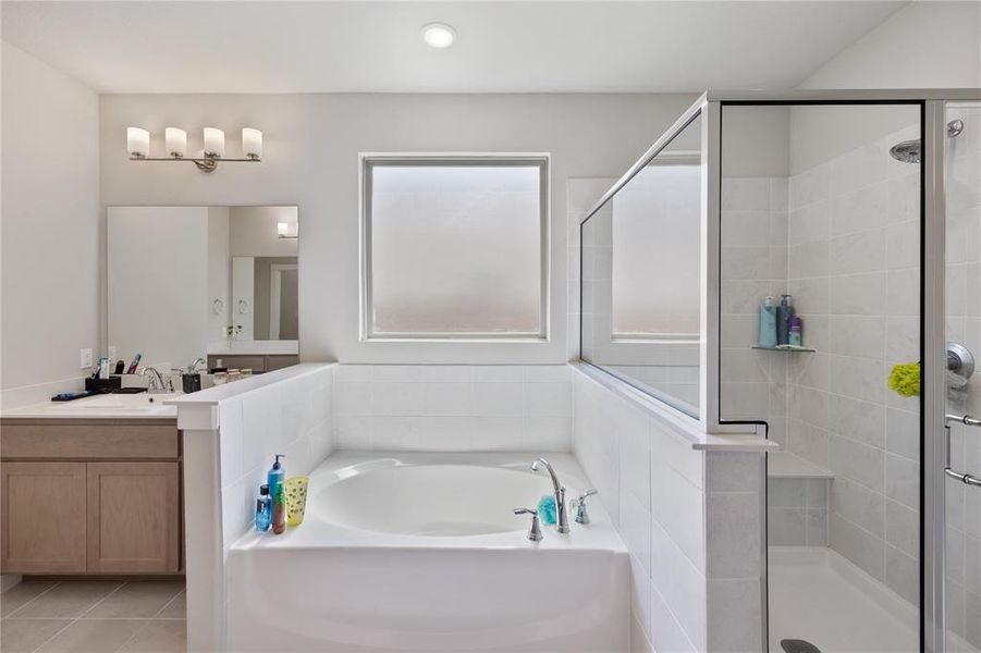 Bathroom featuring tile patterned floors, vanity, and separate shower and tub