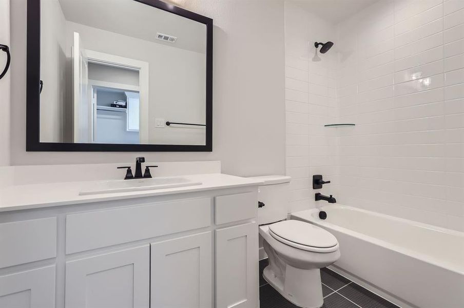 Full bathroom with toilet, tiled shower / bath, vanity, and tile patterned flooring