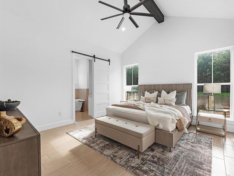 This spacious primary bedroom includes a 14-foot cathedral ceiling, oversized black ceiling fan, and a modernized 5-panel barn door that separates it from the primary bathroom.