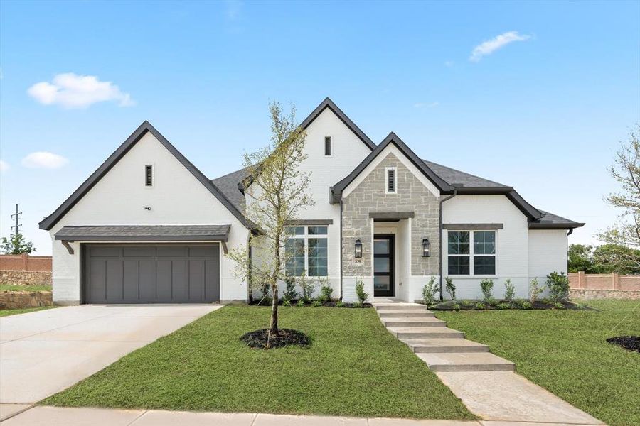 View of front facade featuring a garage and a front lawn