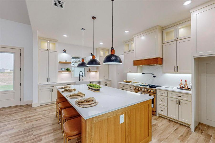 Kitchen featuring a kitchen bar, a center island, high end stainless steel range, and light hardwood / wood-style flooring