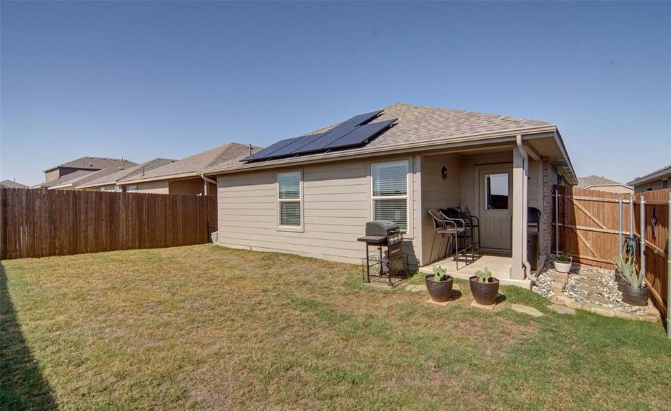 Back of house featuring a patio, solar panels, and a lawn