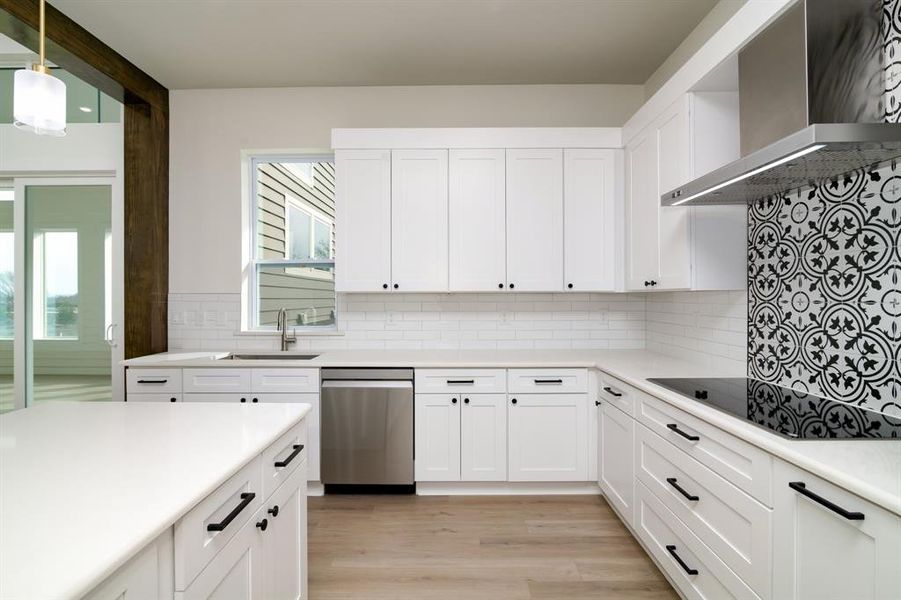 Kitchen featuring dishwasher, sink, wall chimney exhaust hood, and white cabinets