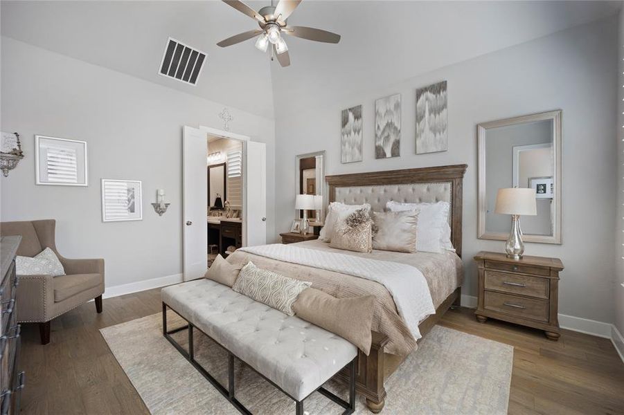 Bedroom with dark wood-type flooring, connected bathroom, and ceiling fan