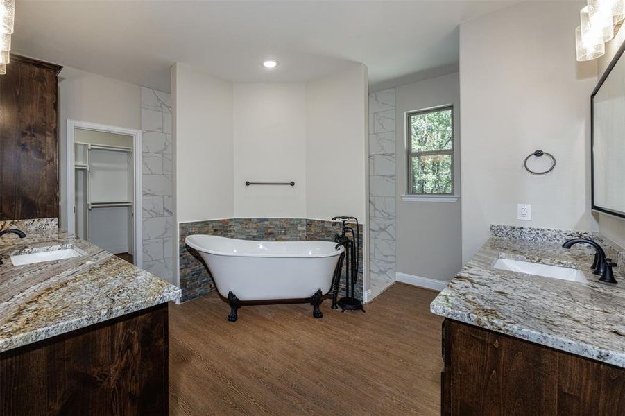 Bathroom with wood-type flooring, vanity, and a tub to relax in