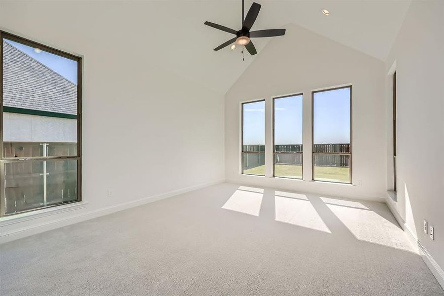 Main bedroom featuring high vaulted ceiling, carpet flooring, and ceiling fan