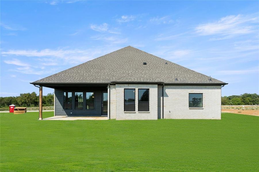 Back of house with a lawn and a patio