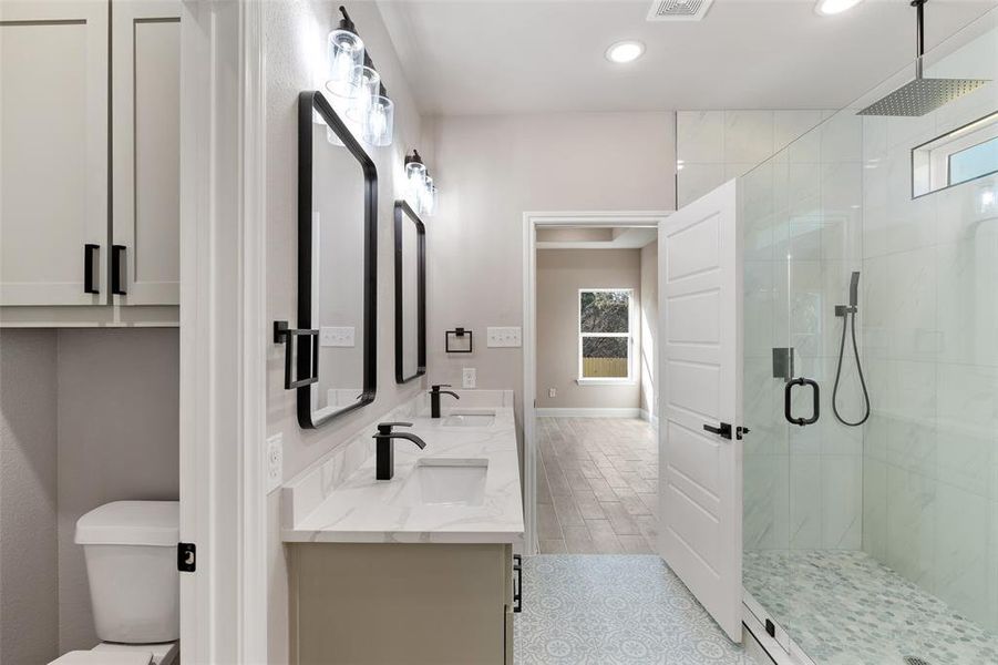 Bathroom featuring a healthy amount of sunlight, dual vanity, a shower with shower door, and tile floors