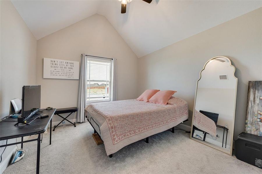 Carpeted bedroom with ceiling fan and high vaulted ceiling