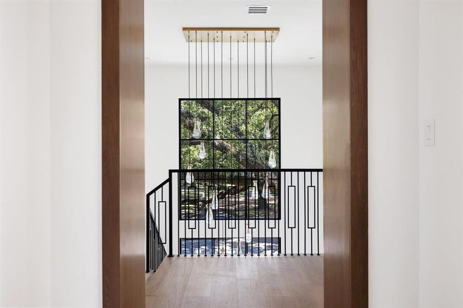 The gorgeous view from the second floor looks out over the front oak tree into the park beyond, a view that's truly captivating when seen from this custom staircase and cased opening.
