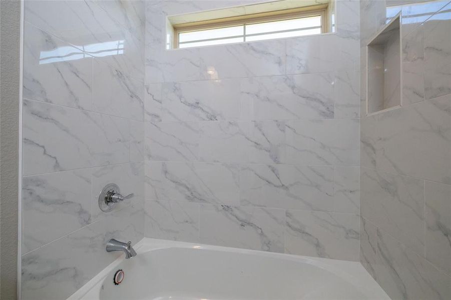 Bathroom featuring tiled shower / bath and a healthy amount of sunlight