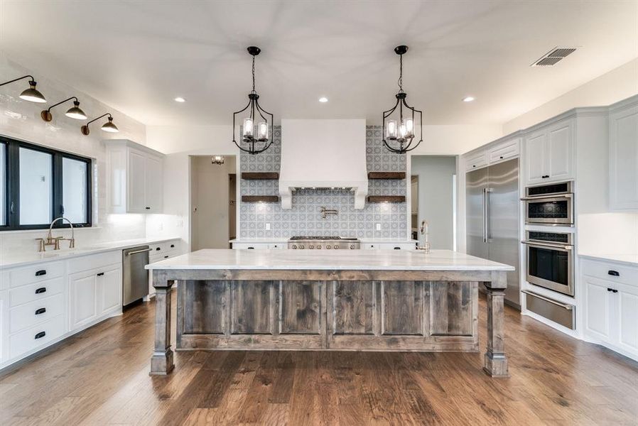 Kitchen with hardwood / wood-style flooring, appliances with stainless steel finishes, a kitchen breakfast bar, and a center island