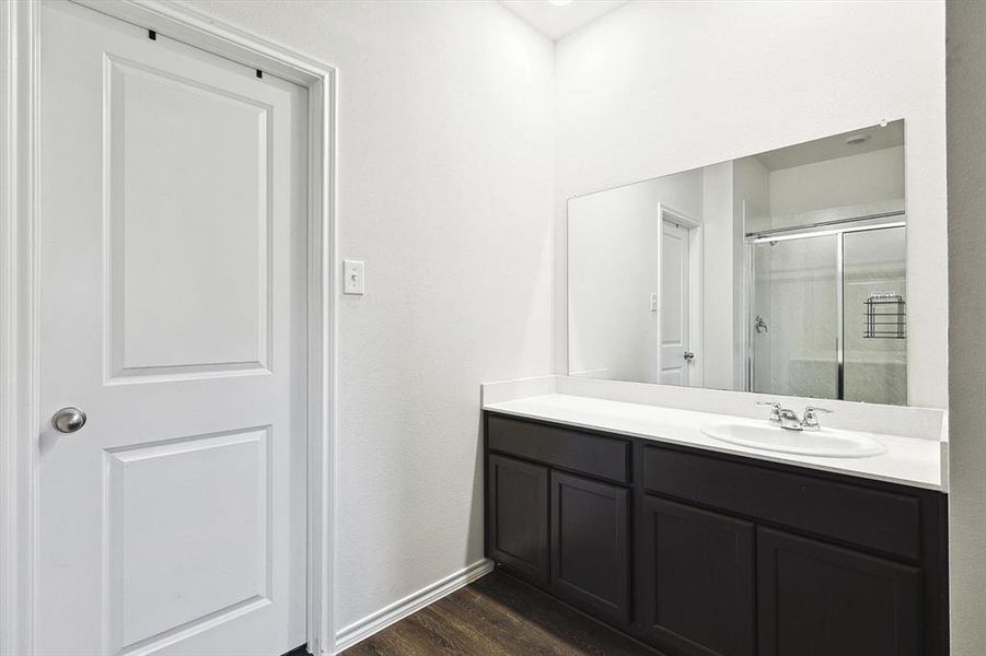 Bathroom featuring hardwood / wood-style floors, a shower with door, and vanity