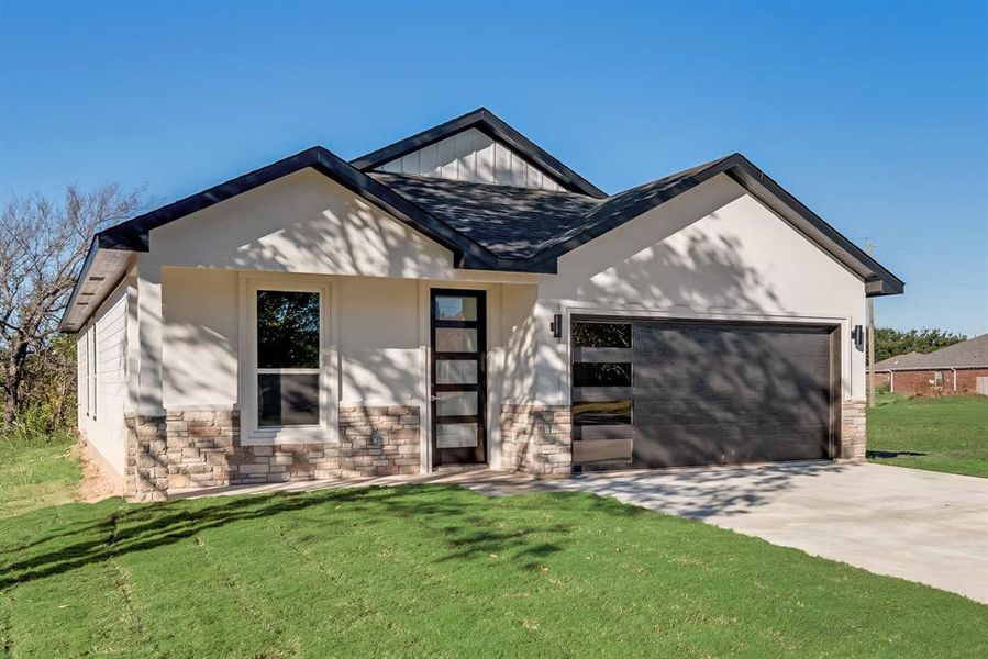 View of front of home featuring a front lawn and a garage