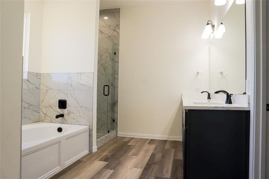 Bathroom featuring plus walk in shower, hardwood / wood-style flooring, and vanity